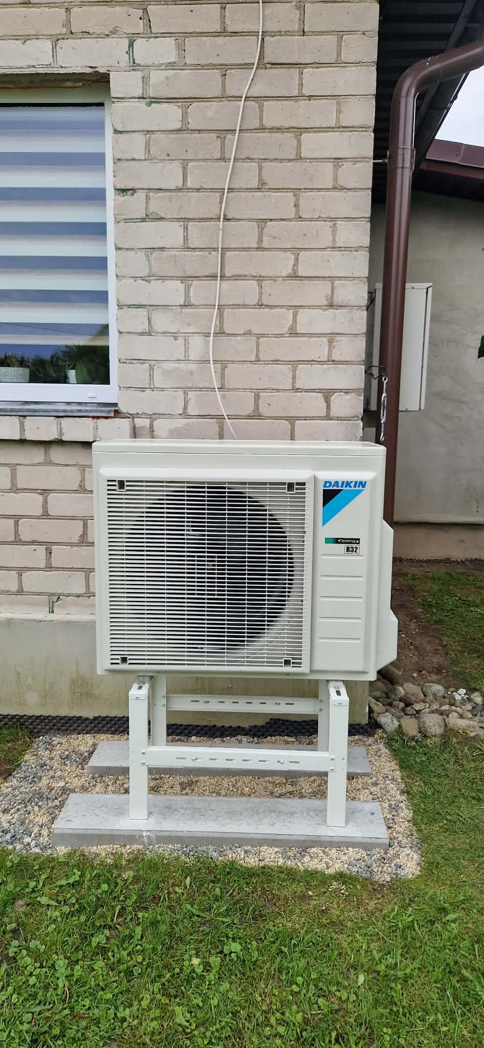 Ant stabilaus metalinio stovo prie namo sumontuotas Daikin lauko blokas